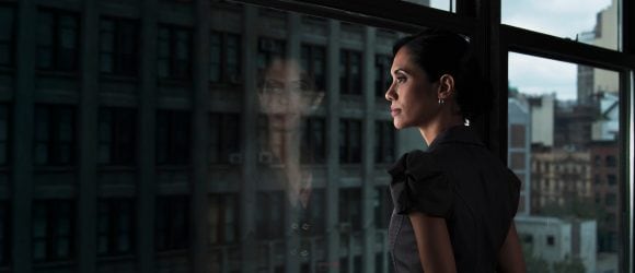 Woman deep in thought, gazing out office window with her reflection