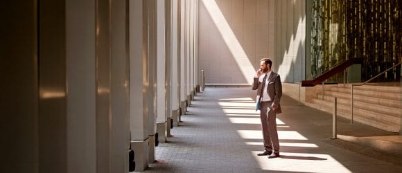 Man on mobile in front of building with dramatic lighting
