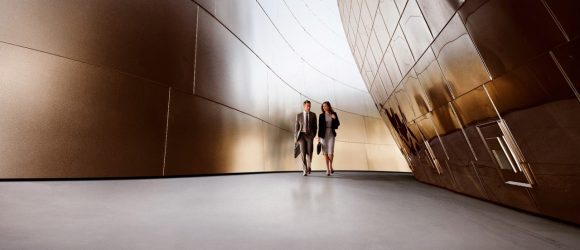 Two business people walking through corridor between buildings.