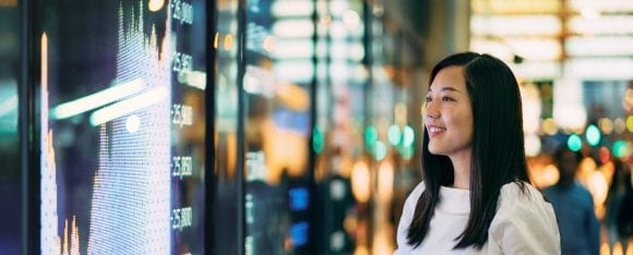 Businesswoman looking at stock exchange market display screen