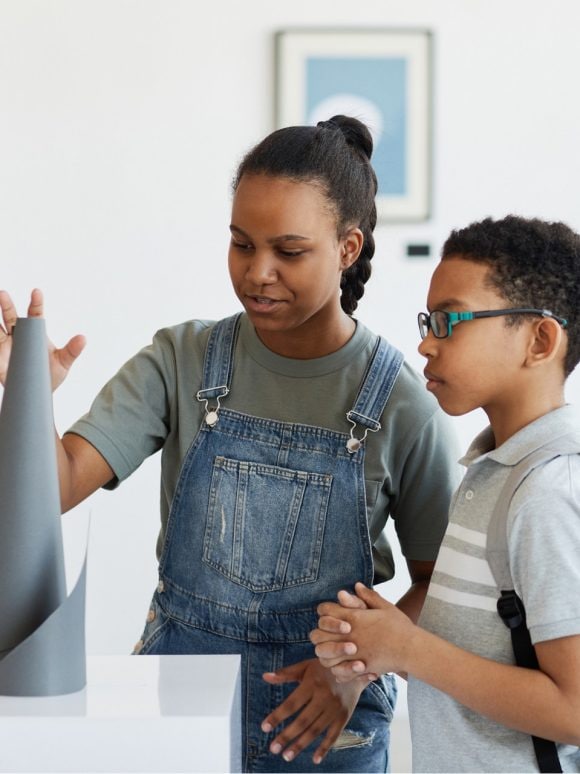 Two young children in art gallery viewing a sculpture.