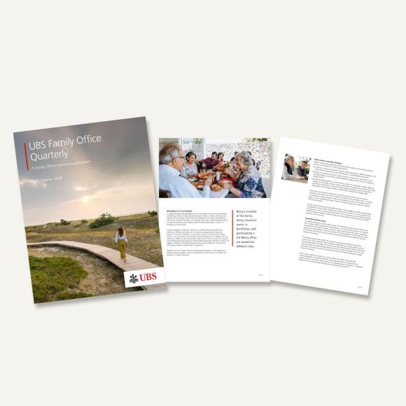 Photograph of a UBS Family Office Quarterly report cover placed on a wooden desk. Cover shows a coastal landscape with a person on a curved boardwalk, “Fourth Quarter 2024” text, and UBS logo at bottom right.