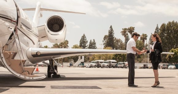 Female businesswoman shaking hands with private jet pilot at airport