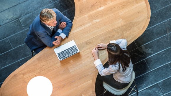 Two business people in meeting at curved desk overhead view