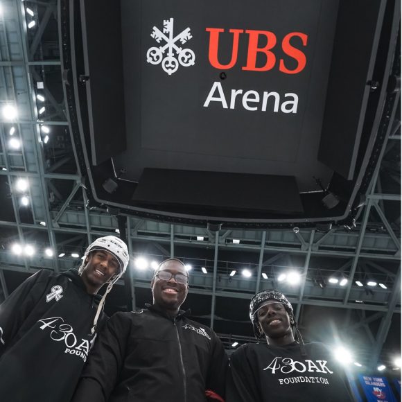 Community impact players standing under ubs Arena sign