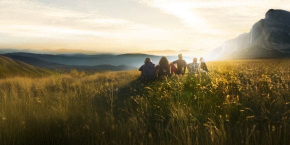 Family of four and their dog inspired by the beauty of nature while viewing the golden sky and landscape on an autumn day