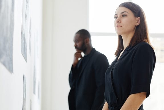 Couple wearing black while looking at photographs in modern art gallery