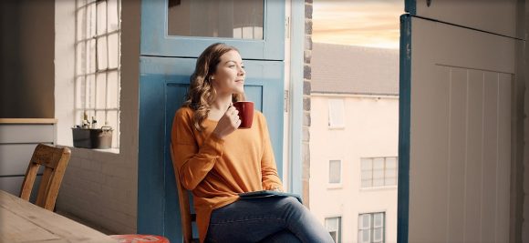 Women seating in a window with a cup of coffee