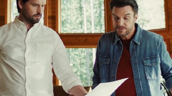 Two brother standing side by side, looking at a document