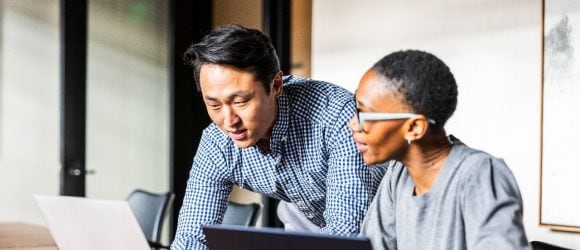 colleagues working on laptops in modern conference room