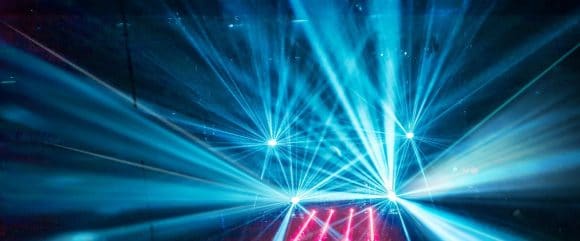 Stage lights cutting through blue and white fog during an event